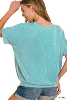 Woman wearing teal ribbed top with dolman sleeves, showcasing relaxed fit and vertical stripes.