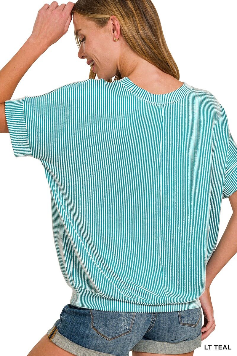 Woman wearing teal ribbed top with dolman sleeves, showcasing relaxed fit and vertical stripes.