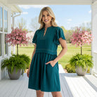 Model wearing the CONFIDENTLY YOU DRESS - Gigio in dark teal, showcasing its soft pleated design and pockets.