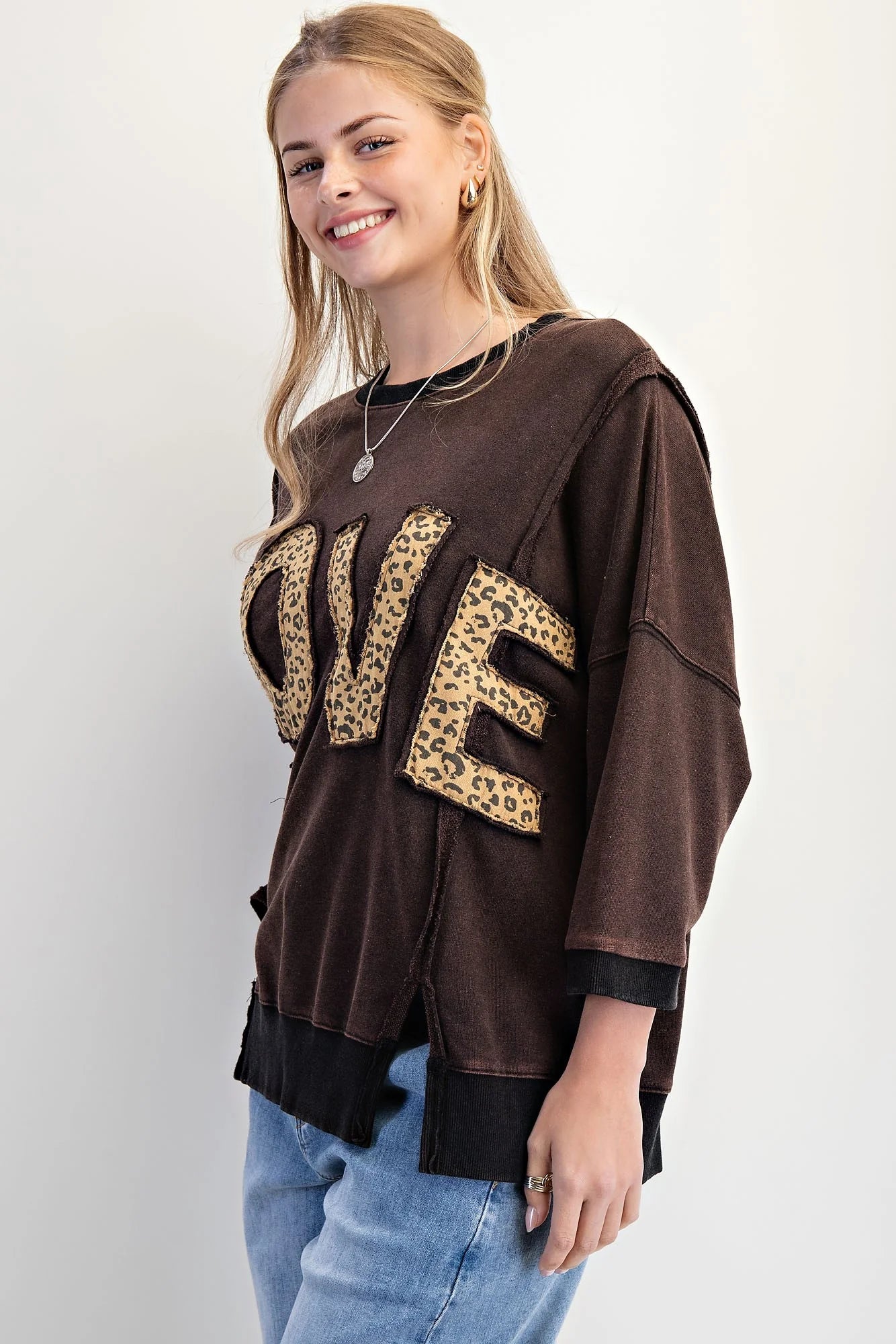 Model wearing LOVE UNTAMED TOP - Easel with leopard print letters, showcasing a comfy oversized style.