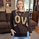 LOVE UNTAMED TOP - Easel in dark wash with leopard print letters, model smiling indoors.