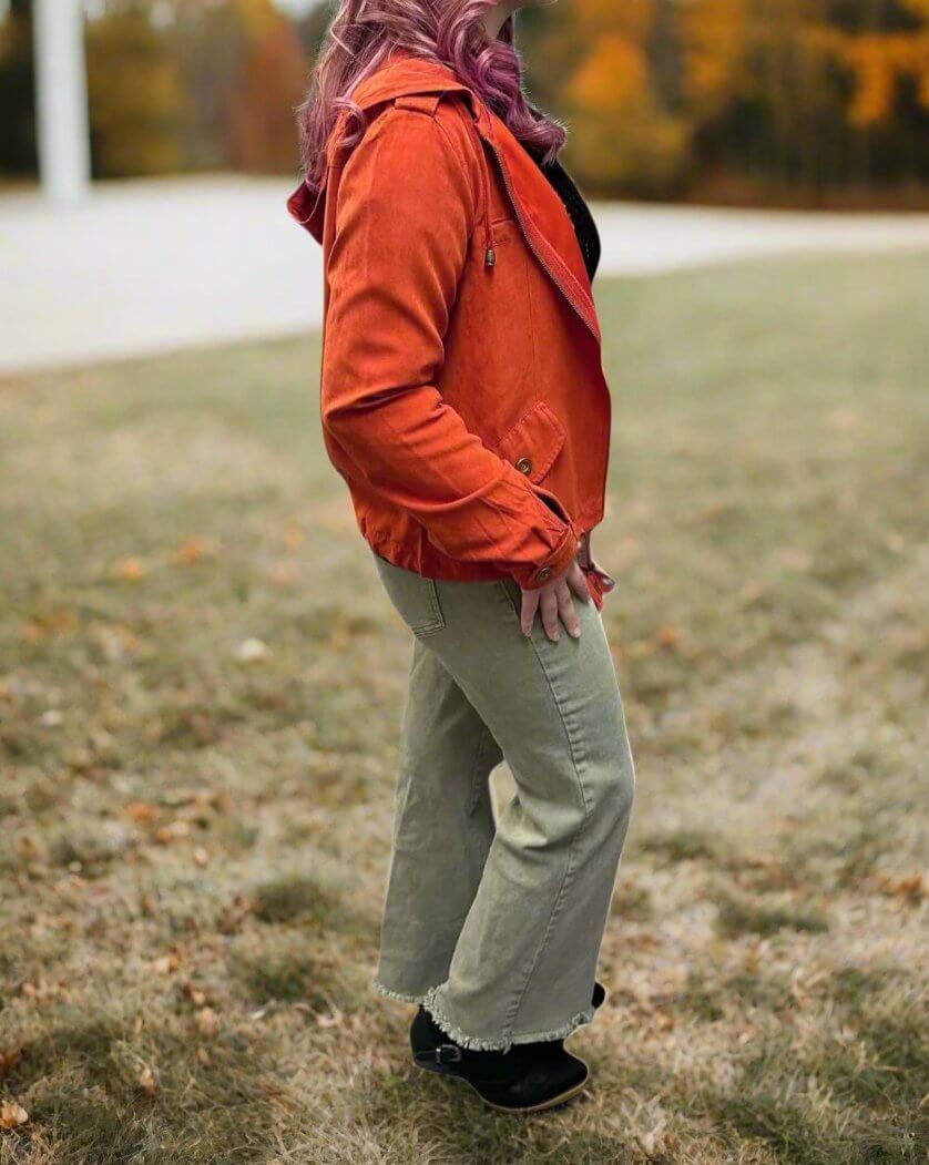 Woman wearing orange Autumn Sunrise Jacket in a grassy field during fall season.