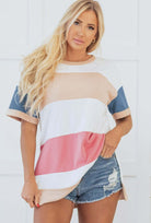 BOLD MOVES TOP displayed on a model, featuring bold stripes in pastel colors, paired with denim shorts.