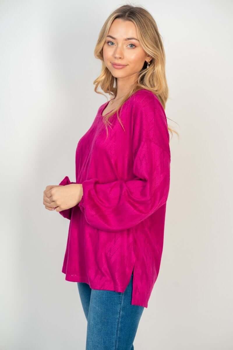 Woman wearing hot pink long sleeve HAPPY WANDERER Top by White Birch with side split, paired with jeans for stylish casual look