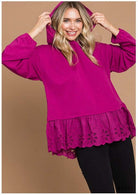 Woman wearing a berry-colored ADVENTURE AWAITS hoodie top with eyelet ruffle and long sleeves by Cotton Bleu.