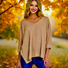 Woman in a toffee jacquard sweater against a backdrop of autumn leaves, showcasing cozy style and effortless elegance.