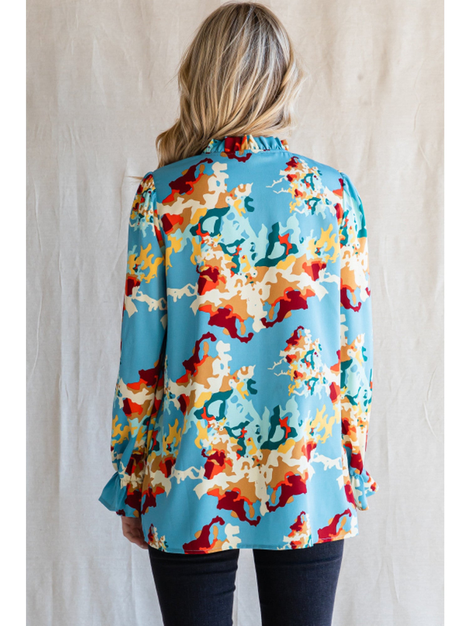 Woman wearing Jodifl Pure Poetry Top with vibrant print and flowy poet sleeves, rear view.