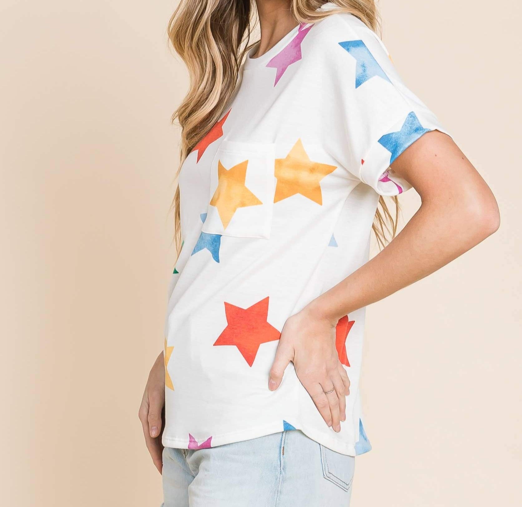 Model wearing a colorful star print soft knit t-shirt with short sleeves and a chest pocket.