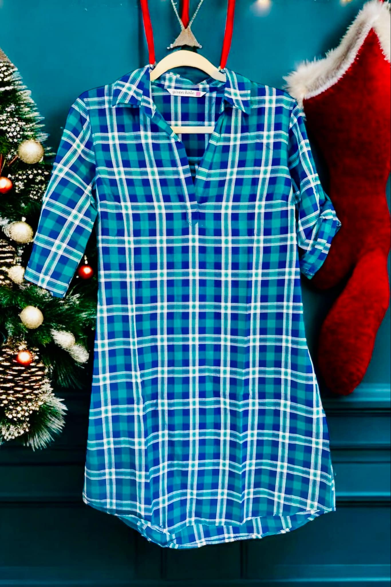 Blue and green plaid dress by Given Kale, hanging near Christmas decorations, perfect for fall or winter style with adjustable sleeves.