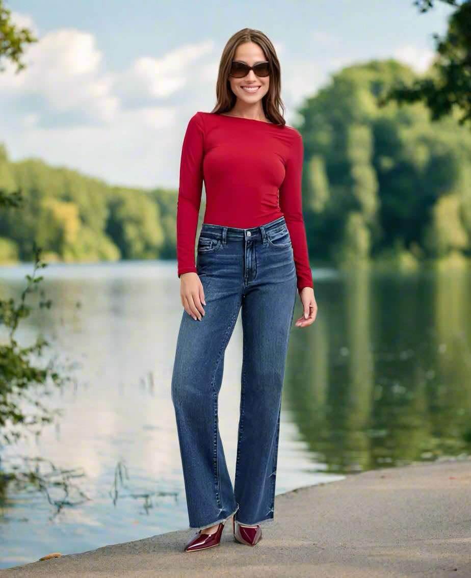 Model wearing JUDY BLUE Mia dark wash midrise wide leg jeans by a scenic lake.