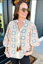 Woman wearing a stylish Painted Horizon Top with a geometric pattern and tassel detail, perfect for casual outings.