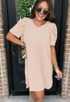 Woman wearing beige Carefree Spirit dress with short puff sleeves, smiling outdoors in casual style.