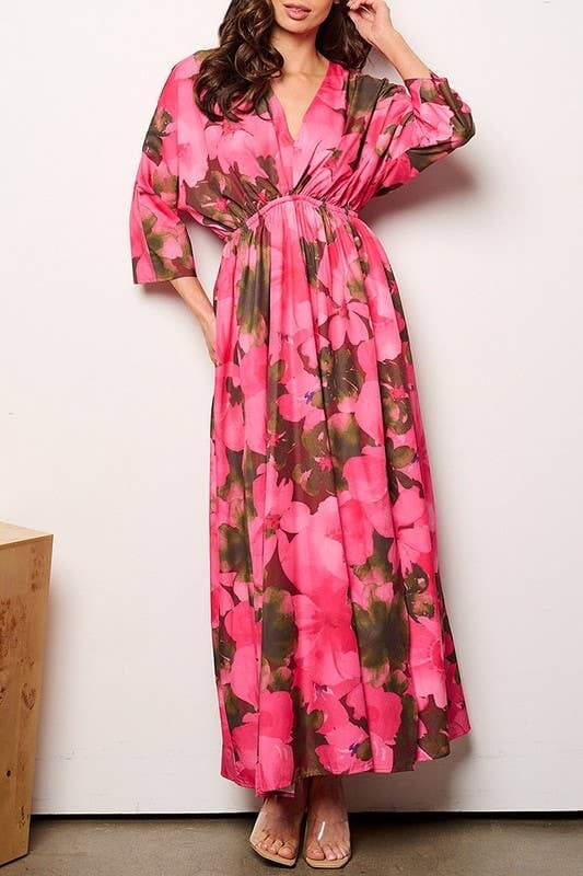 Model wearing a pink floral maxi dress with 3/4 sleeves and elastic waist, showcasing a stylish V-neck design.