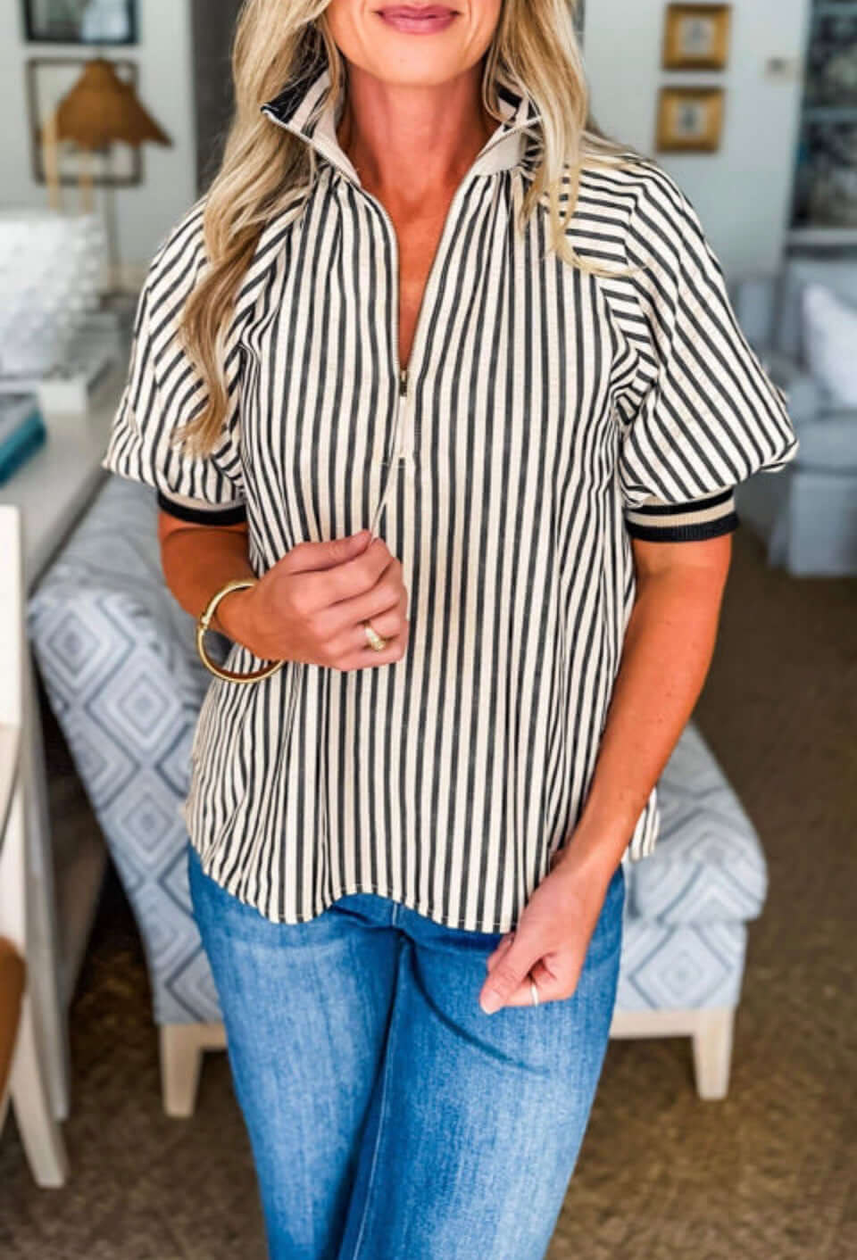 Woman wearing the CLASSIC CURRENT TOP with black stripes and a half zip neckline, styled for a chic look.