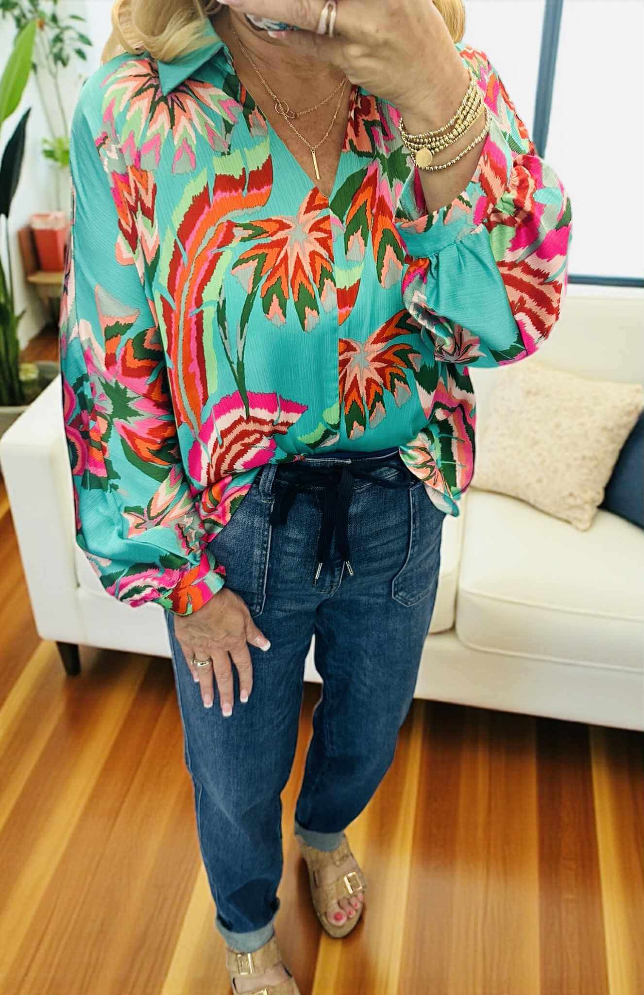 Woman wearing LAGUNA LUXE BLOUSE - JODIFL in vibrant colors paired with casual jeans.