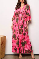 Model wearing a pink floral maxi dress with 3/4 sleeves and V-neckline, showcasing an elastic waist design.