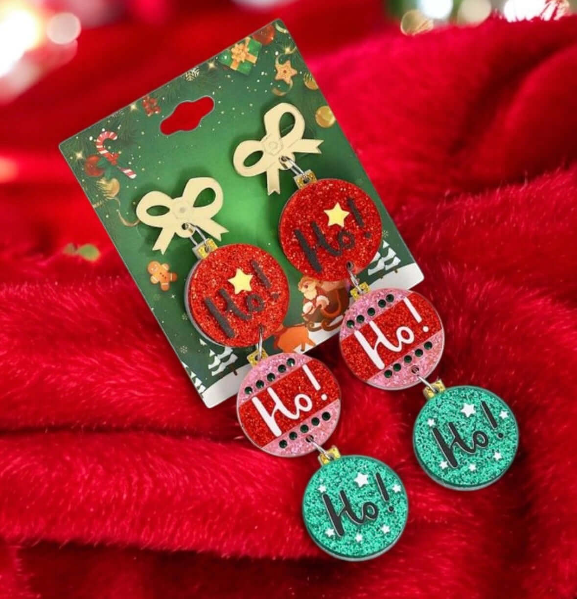 Festive HO HO HO earrings with gold bow, red and green Christmas balls, perfect for holiday outfits and spreading cheer.