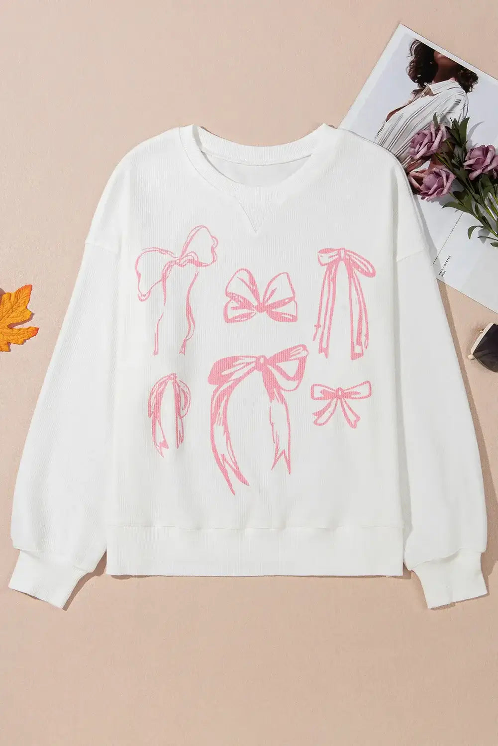 Softly Tied Crewneck featuring pink bowknot pattern on a white corded long sleeve top.