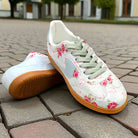 Floral vintage sneakers with mint laces and gum soles on a cobblestone surface.