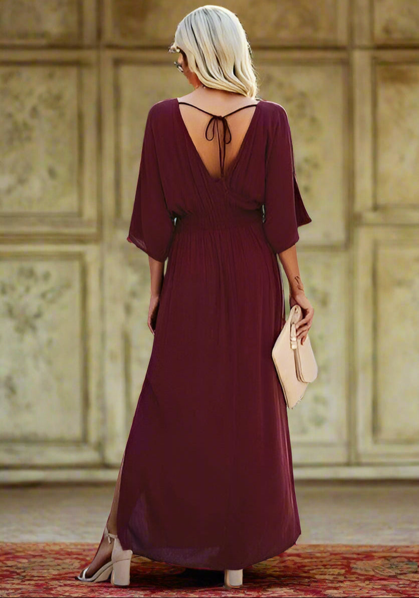 Back view of a woman in a burgundy deep V neck maxi dress with ruffles, perfect for casual outings.