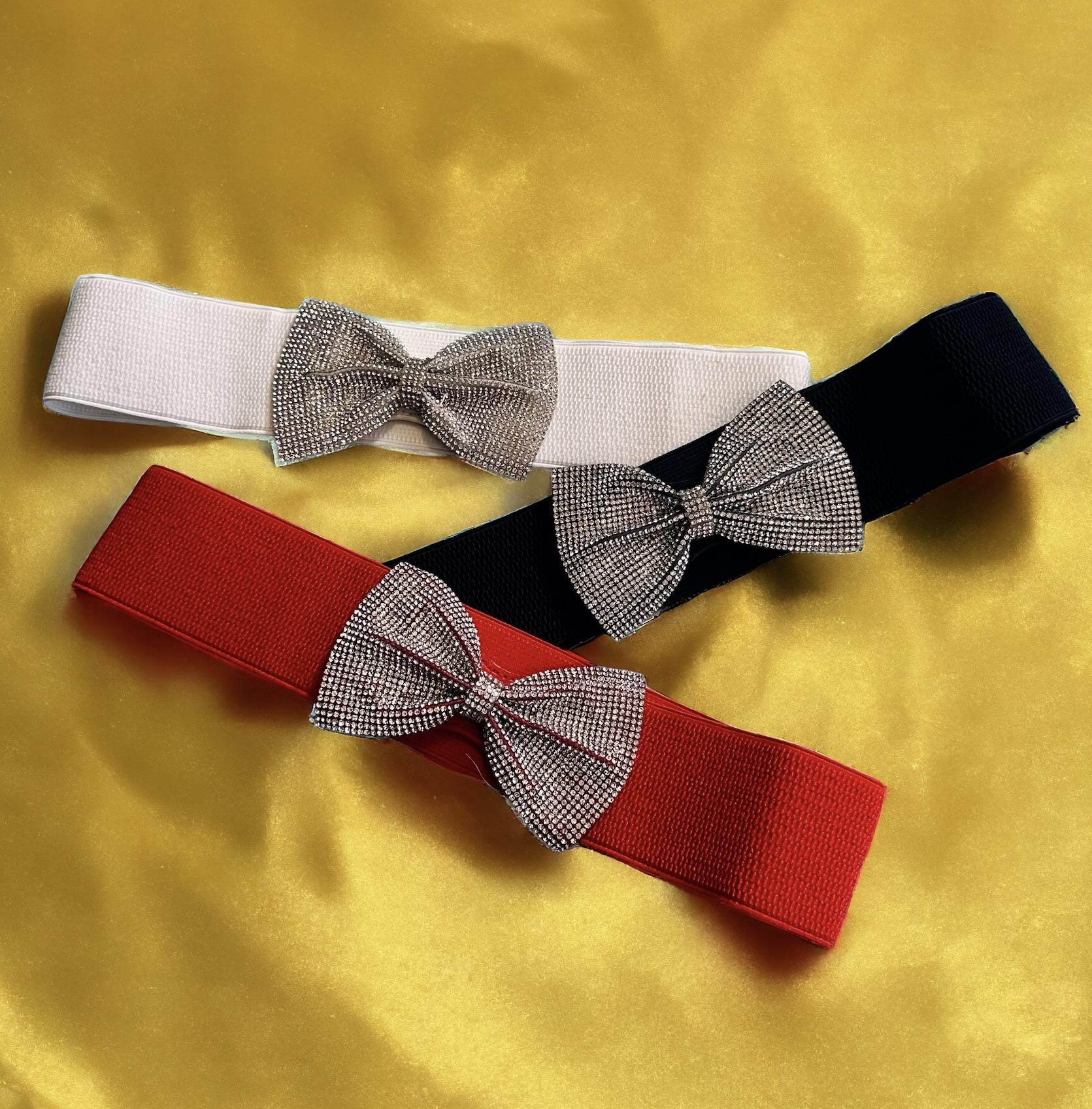 Elastic belts in red, white, and black with rhinestone bows, perfect for adding sparkle to your outfit.