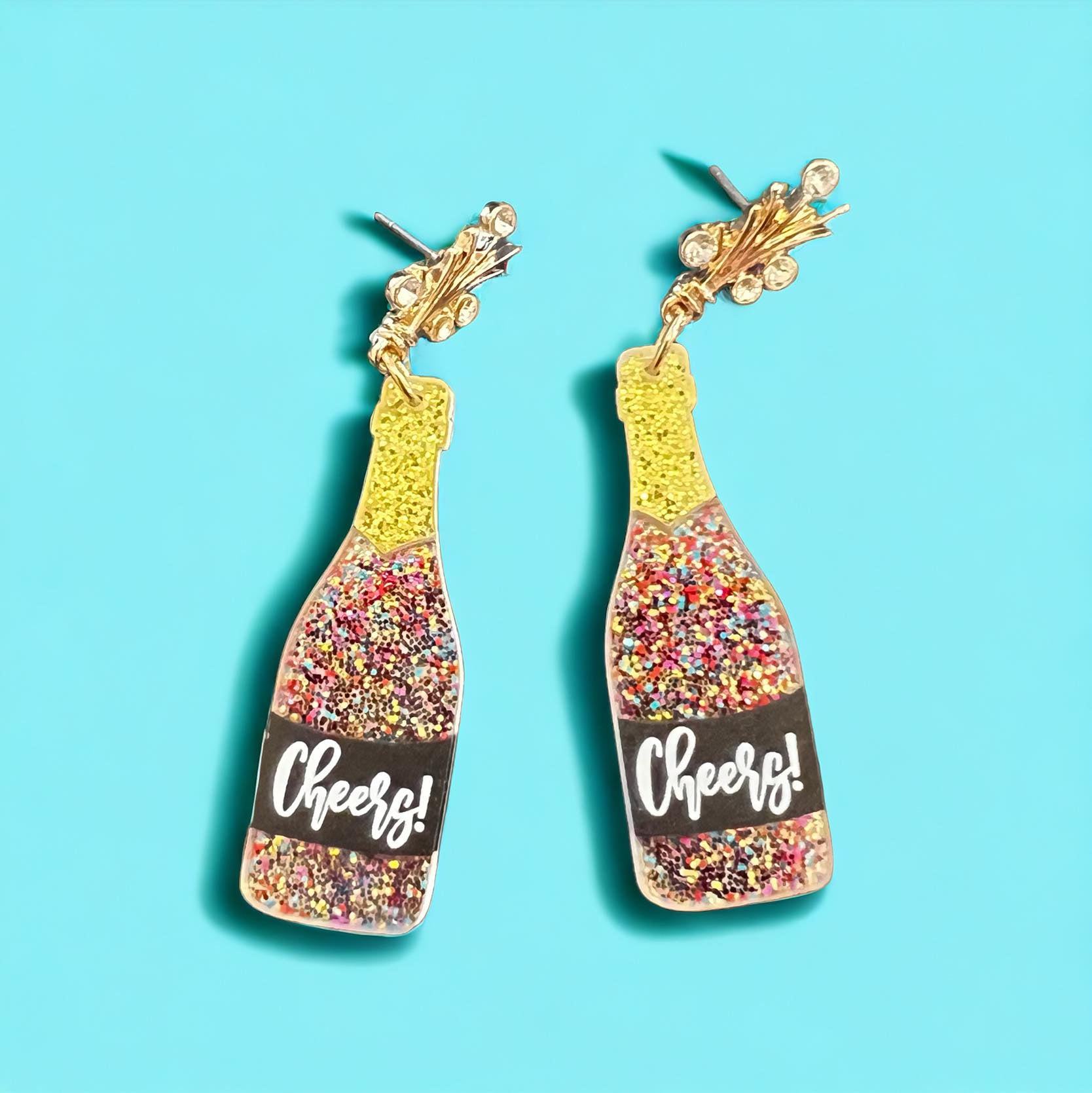 Glittery champagne bottle earrings with 'Cheers!' label, perfect for celebrations and festive outfits.
