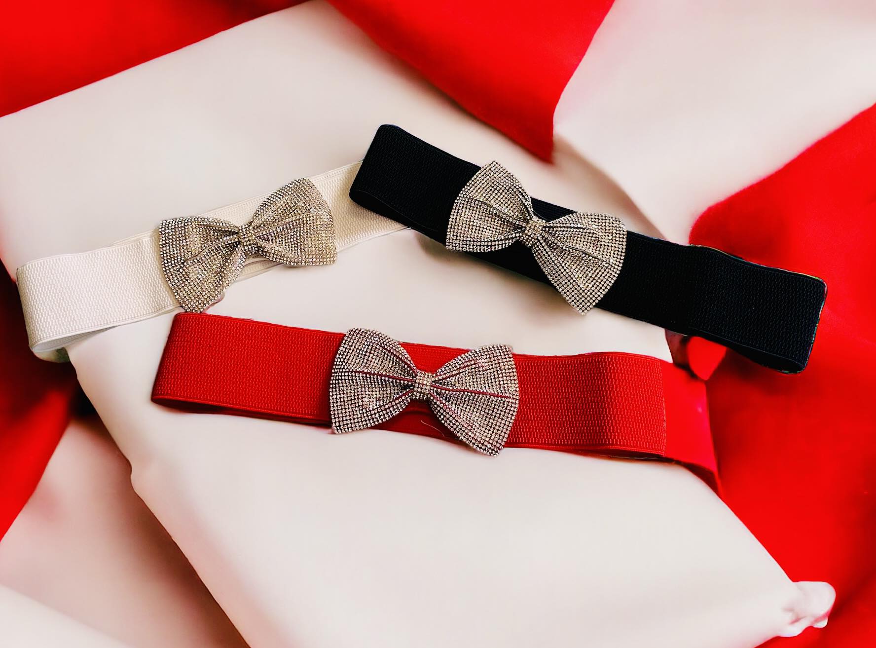 Stylish elastic belts in red, white, and black with rhinestone bows, perfect for adding sparkle to any outfit.