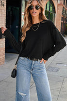 Model wearing the JET SET TOP in black with casual jeans and sunglasses, showcasing a stylish streetwear look.