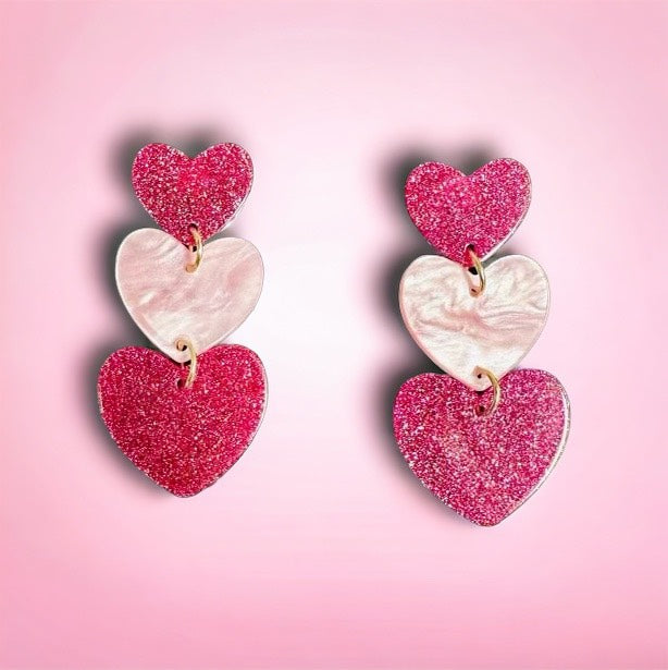 TICKLED PINK Earrings by Teal Tiger Boutique $8.00 These TICKLED PINK Earrings feature a trio of hearts in hot pink and light pink hues, adding a playful pop of color to any outfit. Made with lightweight acrylic, these pierced earrings are a fun and funky