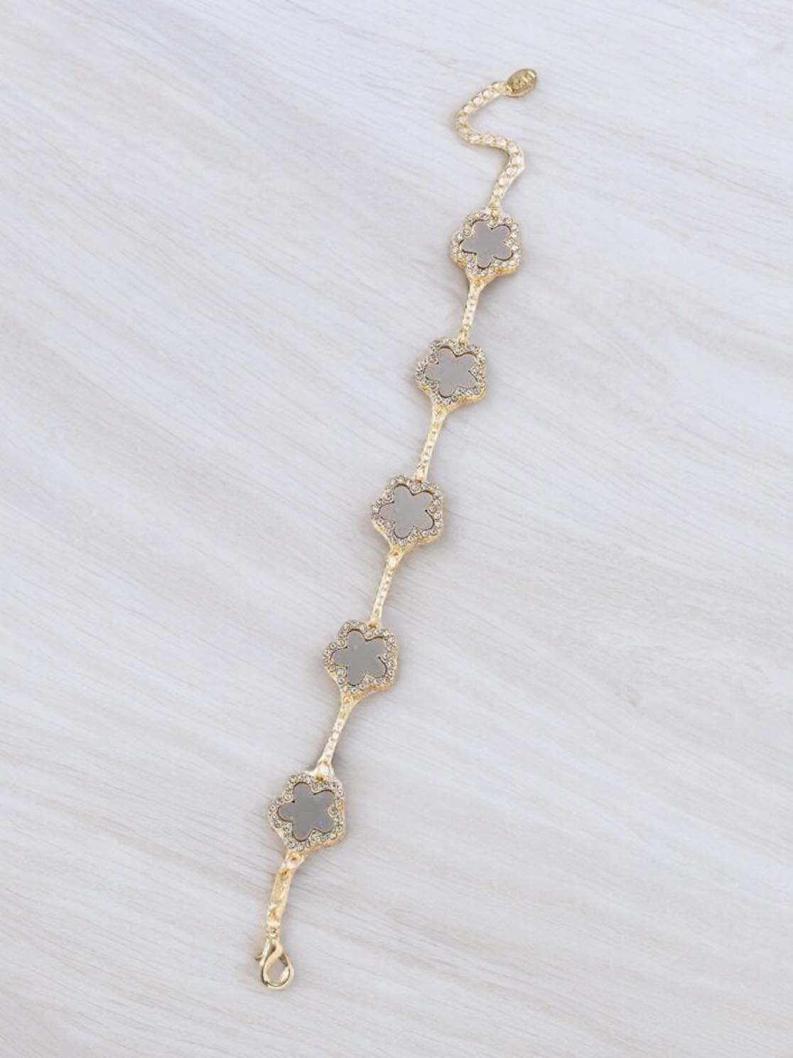 RHINESTONE CLOVER Bracelet (taupe) by Teal Tiger Boutique $14.00 Evoke sophistication and elegance with this luxurious taupe gray clover bracelet adorned with sparkling rhinestones, set against a beautiful gold-toned base. Teal Tiger Boutique