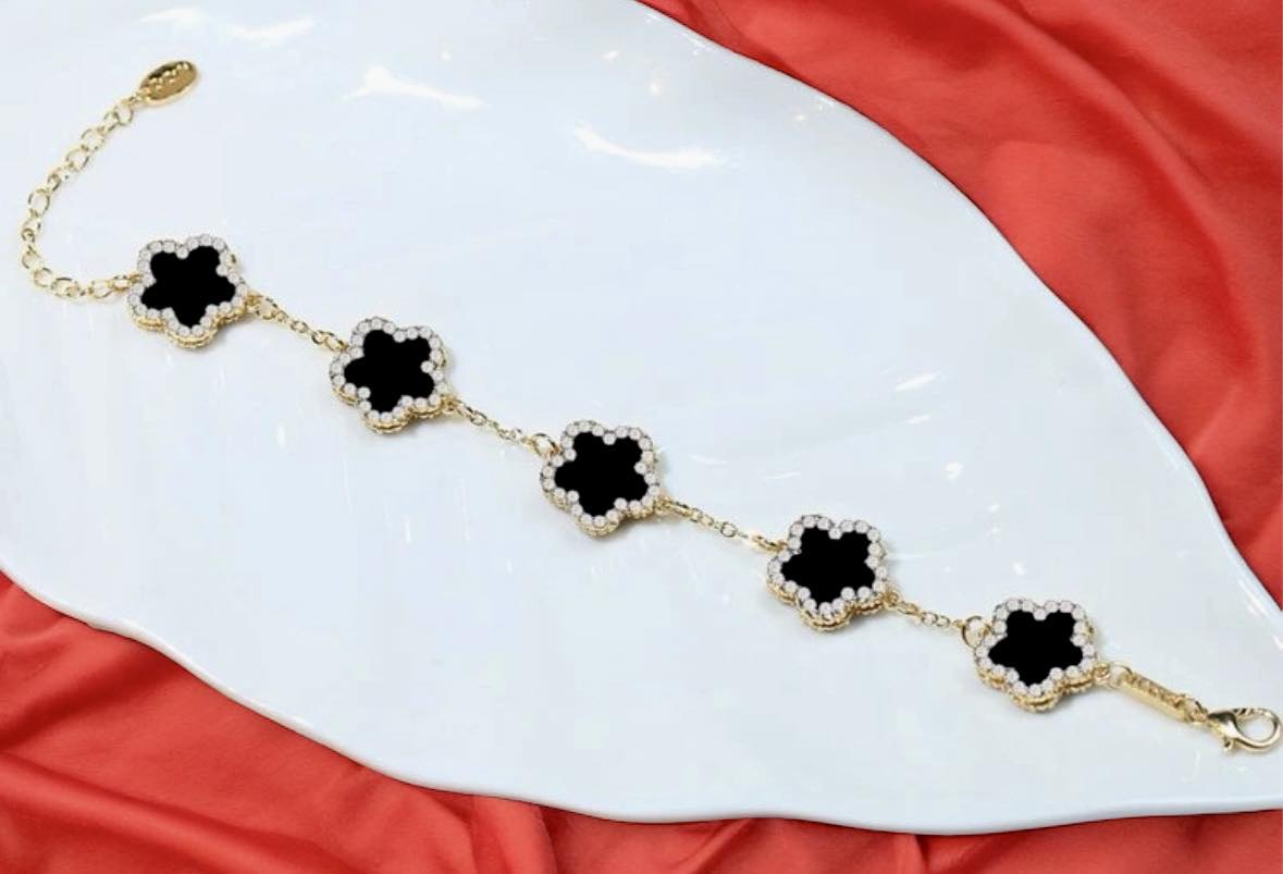 RHINESTONE CLOVER Bracelet (black) by Teal Tiger Boutique $14.00 Evoke sophistication and elegance with this luxurious black clover bracelet adorned with sparkling rhinestones, set against a beautiful gold-toned base. Teal Tiger Boutique