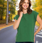 Smiling woman wearing a green Woodland Whisper Tee in a scenic forest setting.