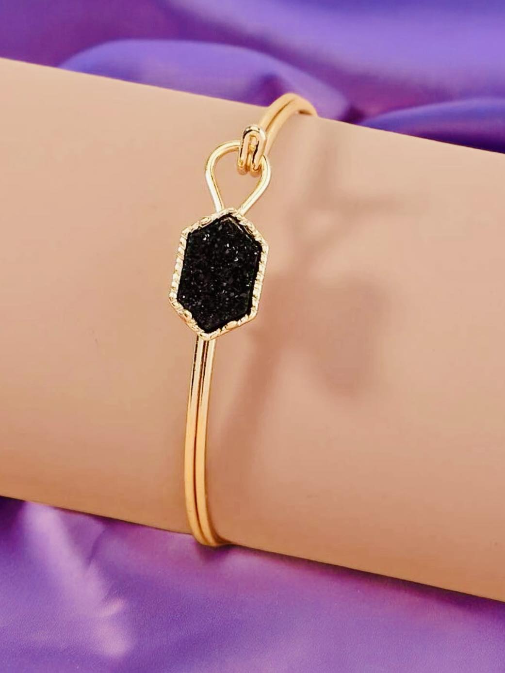 SPARKLING SABLE Bracelet with sable geometric stone, gold tone bangle, and hook closure on a soft background.