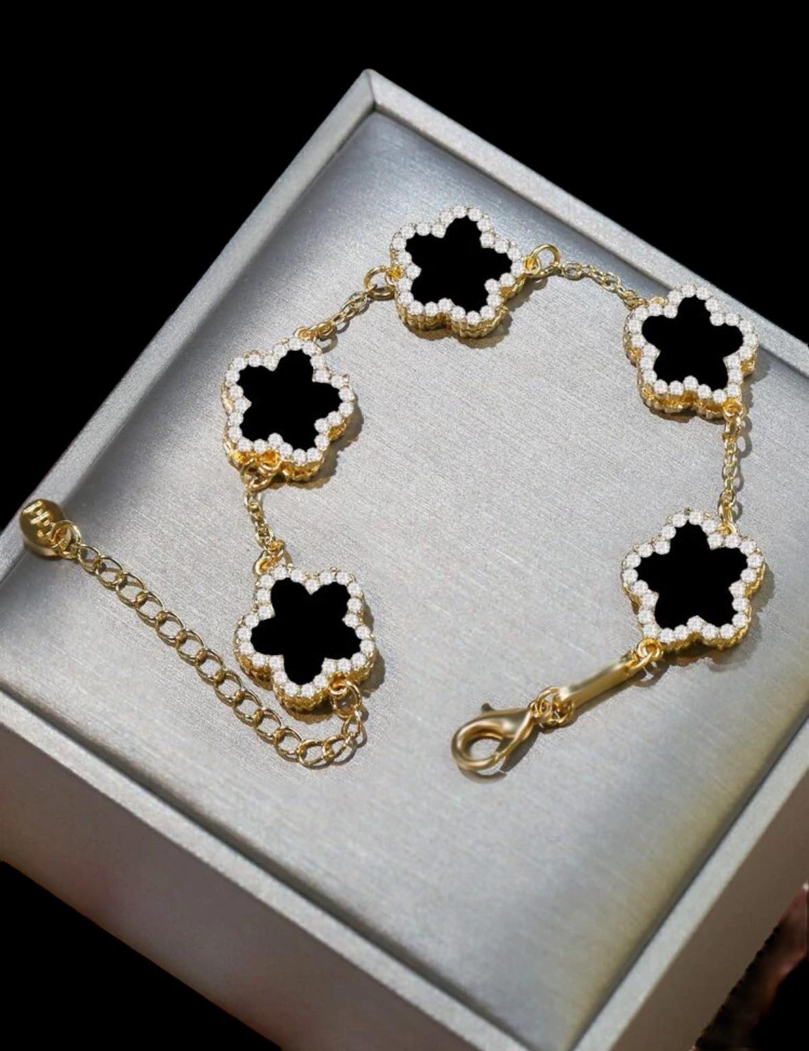 RHINESTONE CLOVER Bracelet (black) by Teal Tiger Boutique $14.00 Evoke sophistication and elegance with this luxurious black clover bracelet adorned with sparkling rhinestones, set against a beautiful gold-toned base. Teal Tiger Boutique