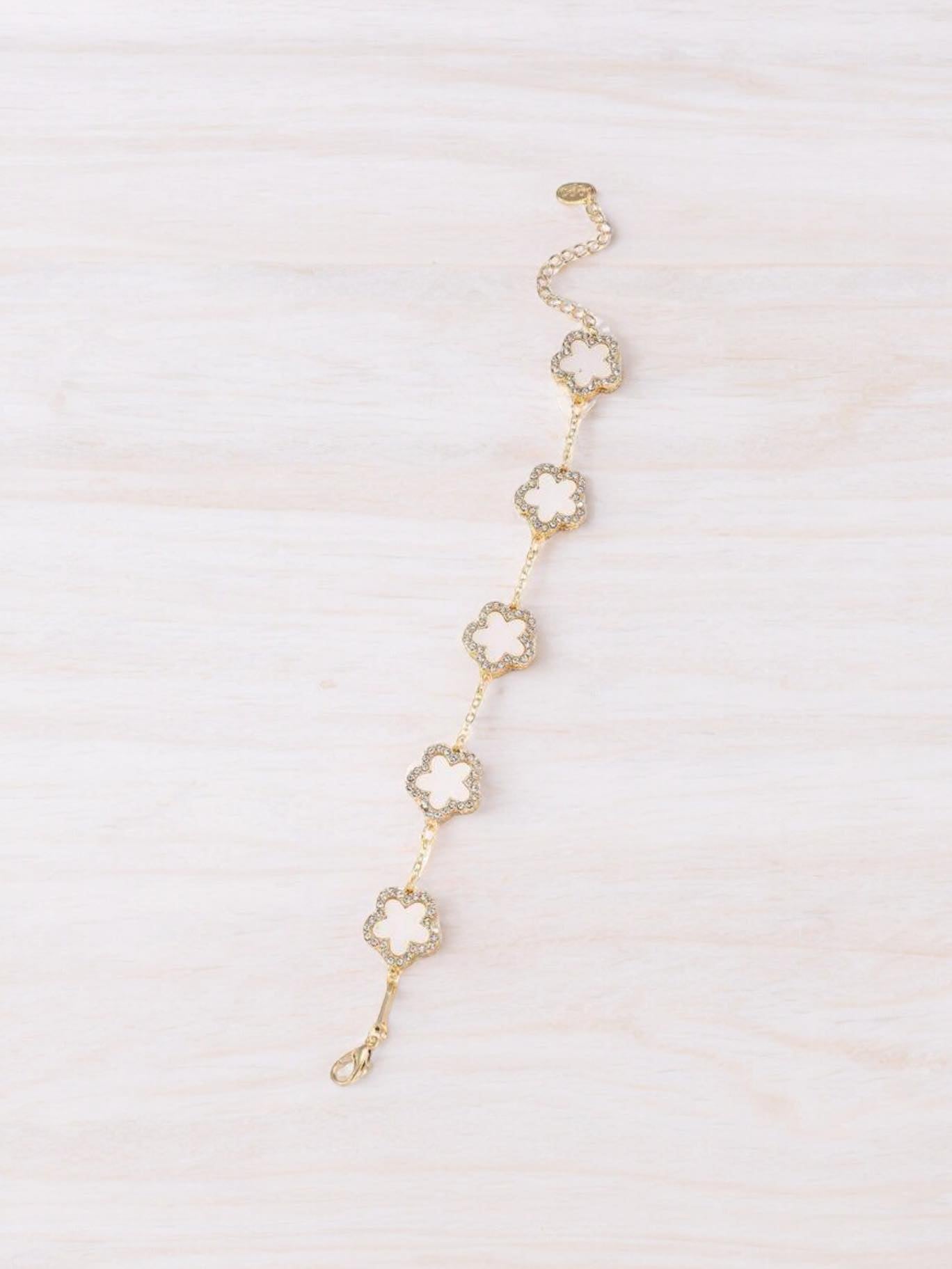 RHINESTONE CLOVER Bracelet (white) by Teal Tiger Boutique $14.00 Evoke sophistication and elegance with this luxurious white clover bracelet adorned with sparkling rhinestones, set against a beautiful gold-toned base. Teal Tiger Boutique