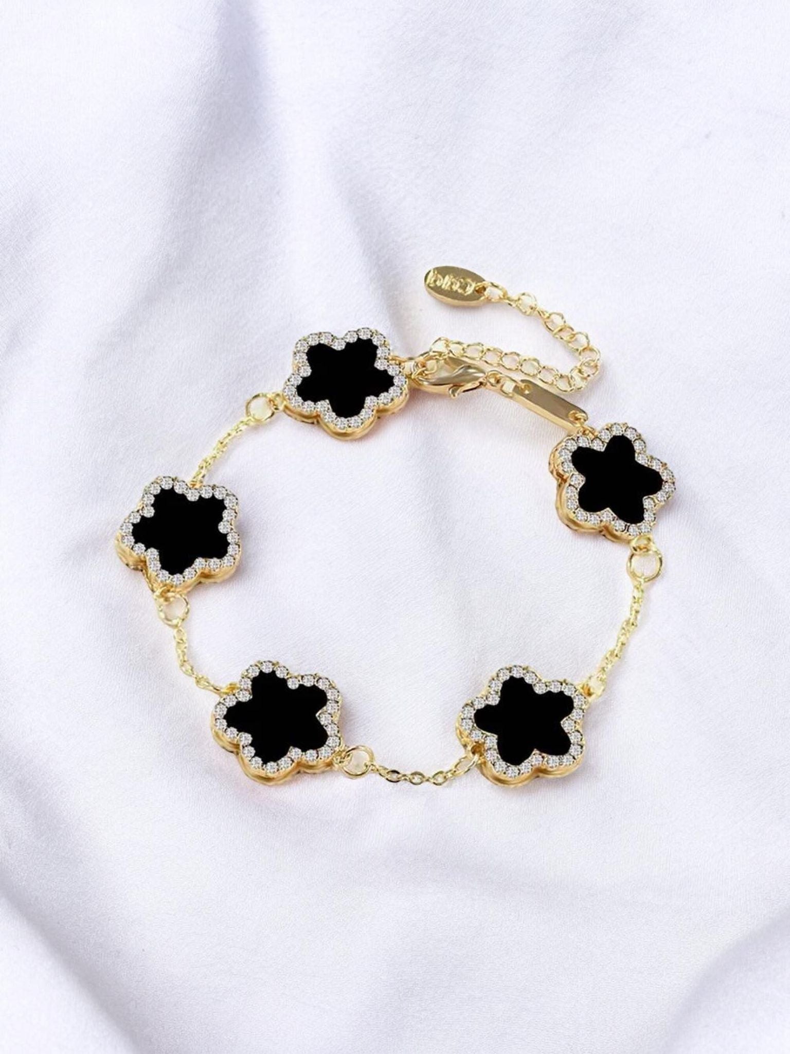 RHINESTONE CLOVER Bracelet (black) by Teal Tiger Boutique $14.00 Evoke sophistication and elegance with this luxurious black clover bracelet adorned with sparkling rhinestones, set against a beautiful gold-toned base. Teal Tiger Boutique