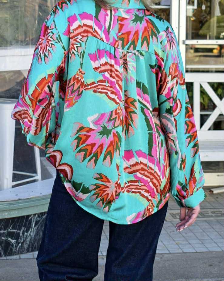 Vibrant back view of LAGUNA LUXE BLOUSE - JODIFL featuring colorful floral patterns in teal, pink, and orange.