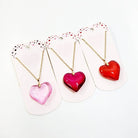 Assorted heart-shaped pendant necklaces in pink, red, and purple, perfect for Valentine's Day gifts.