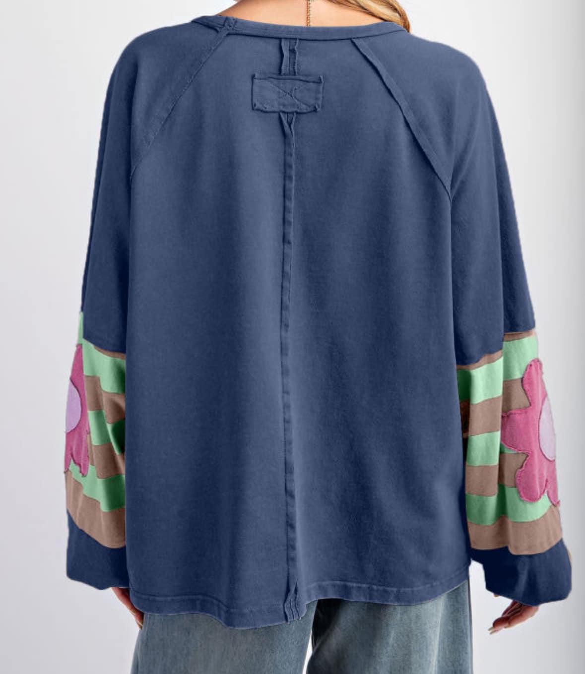 Blue oversized pullover with vintage flair, featuring bubble sleeves, colorful stripe pattern, and raw cut details for casual style.