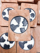 Wooden wick candles featuring cow print design, 100% soy wax, in rounded dough bowl form.