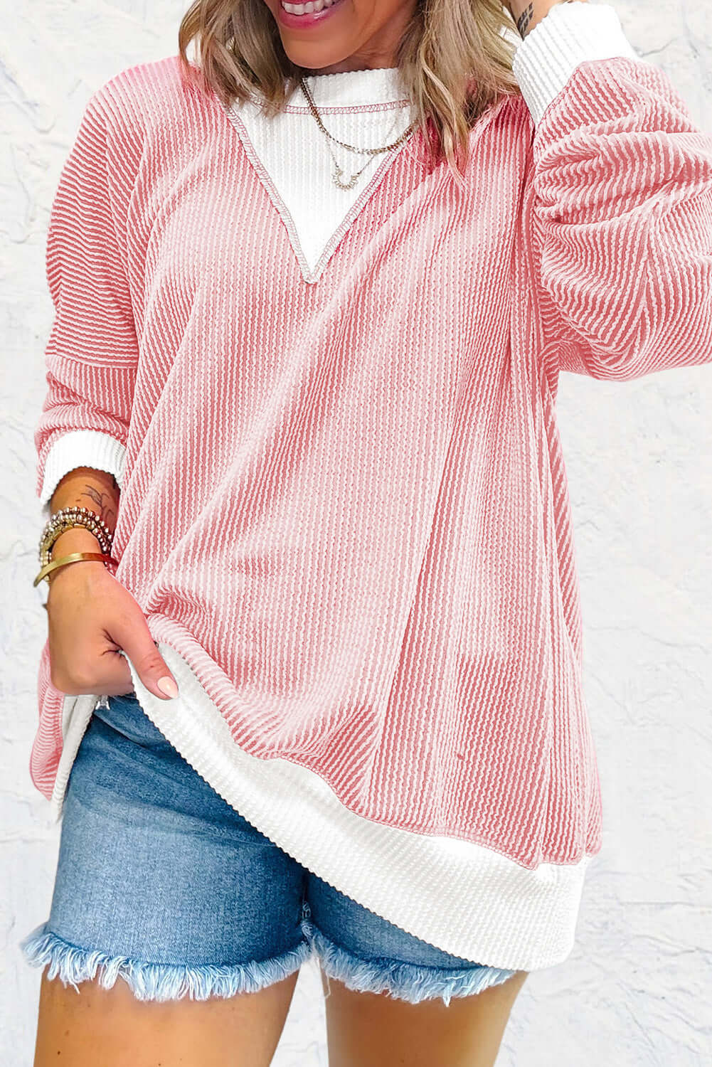 Casual pale pink top with textured corded knit and drop shoulder design paired with denim shorts. Perfect for relaxed style.