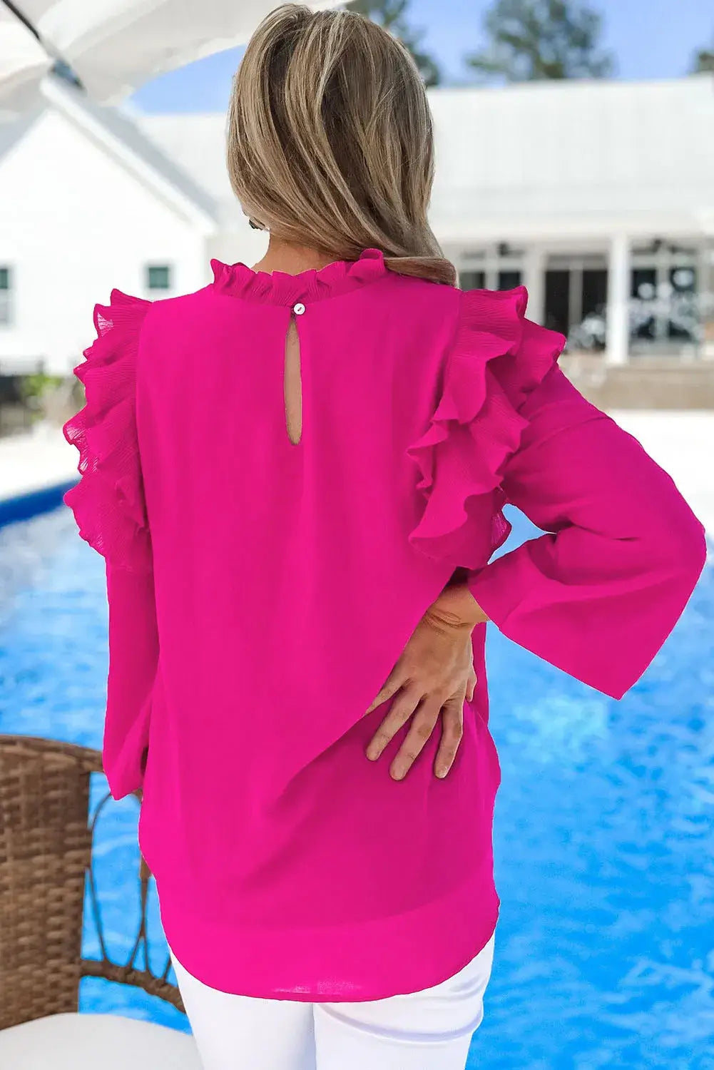 Back view of the Rose' All Day Top in Hot Pink with ruffle trim and keyhole detail, styled by a woman by a pool.