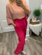 Woman modeling fuchsia Pink Power Joggers with cute belt and elastic waist, paired with a light pink top.