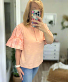 Stylish peach Ruffled Breeze cotton top with ruffle sleeves, perfect for a chic outfit.