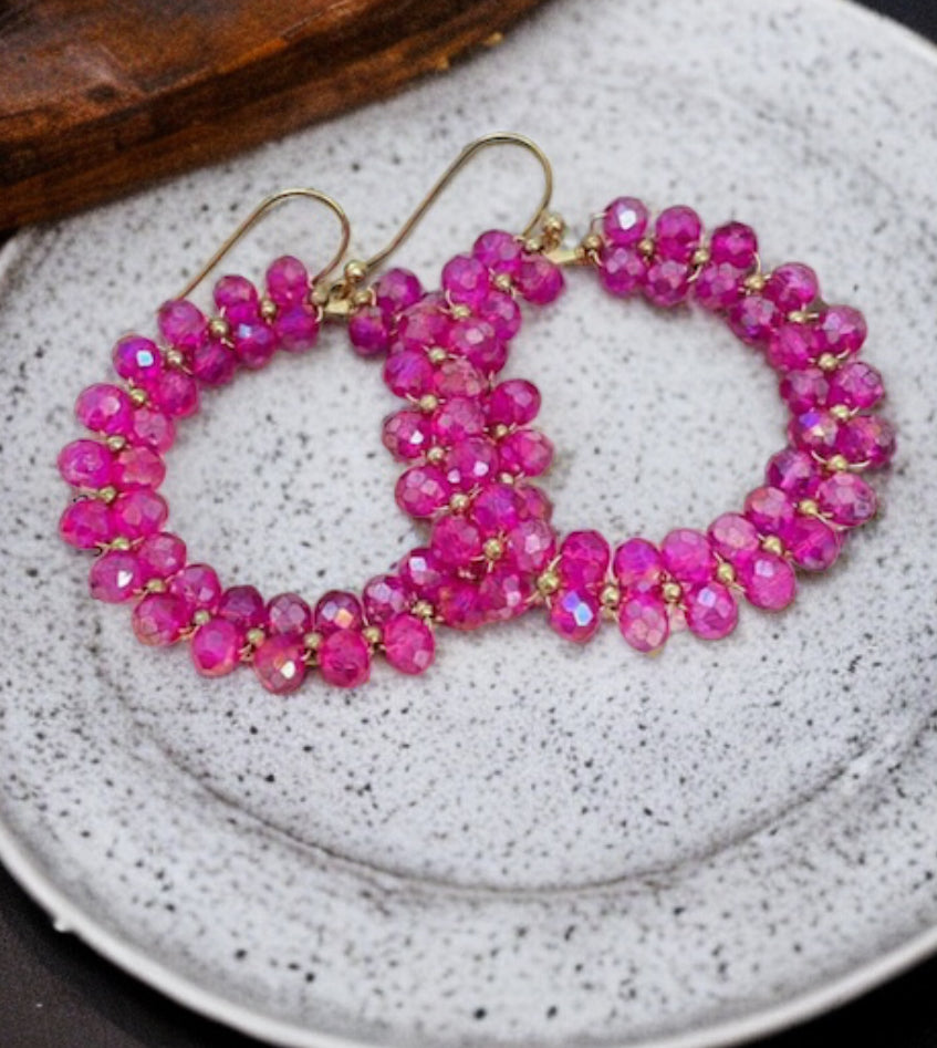 Gold tone hoops adorned with vibrant hot pink jewels, perfect for adding a pop of color to any outfit.