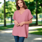 Woman wearing a light rose Air Kiss Top by Zenana in a sunny park setting.
