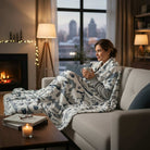 Cozy woman enjoying a warm beverage while wrapped in a SNOWY MOUNTAIN PLUSH THROW BLANKET by the fireplace.