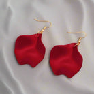 Red ruffle hoop earrings by Vivian-Lu with gold tone hooks on a soft fabric background.