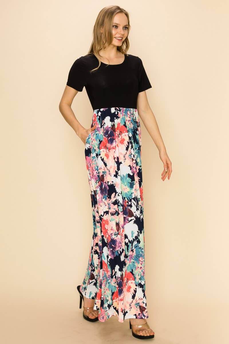 Elegant woman wearing the Raven Radiance Maxi Dress with a black top and colorful floral skirt.