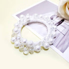 Charmed Twists hair tie with glass beads and faux pearls on a pastel background, stylish and elegant for all hair types.